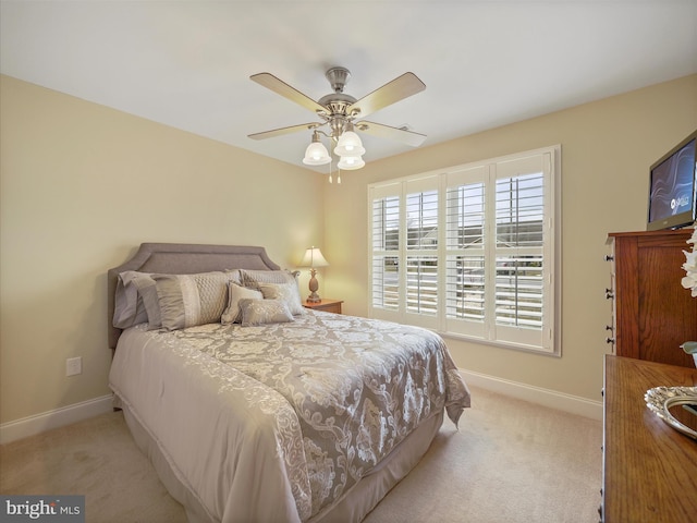 bedroom featuring light colored carpet, ceiling fan, and baseboards