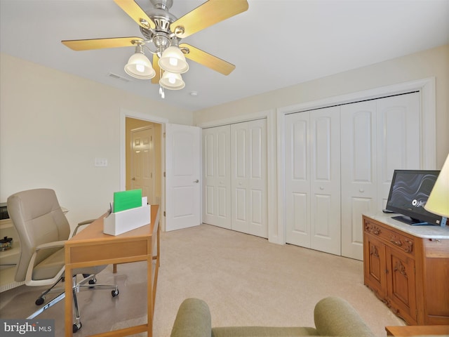 office space featuring a ceiling fan, light colored carpet, and visible vents