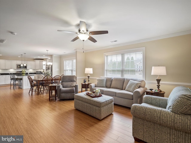 living area with light wood-style floors, visible vents, ornamental molding, and a ceiling fan