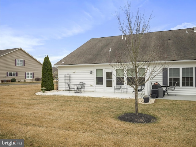 back of property featuring a yard, a patio, and a shingled roof