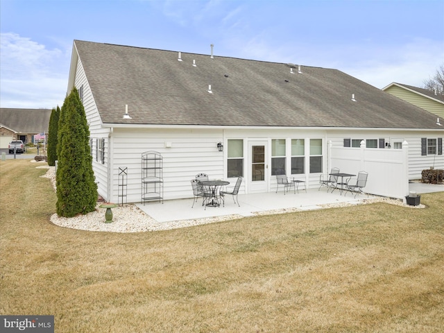 rear view of house featuring a patio area, a shingled roof, and a lawn