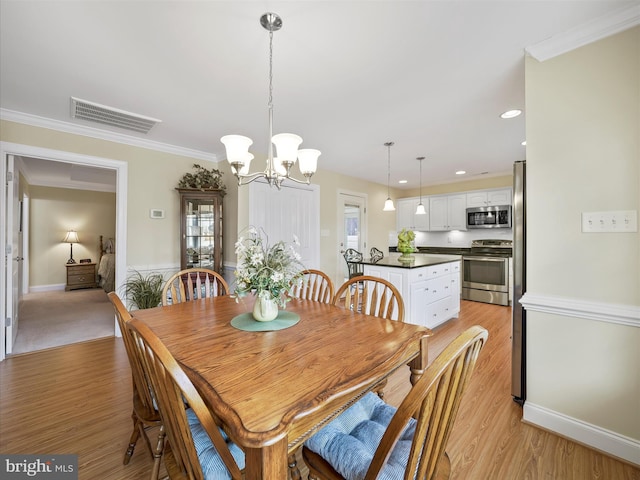 dining area with ornamental molding, visible vents, a notable chandelier, and light wood-style flooring