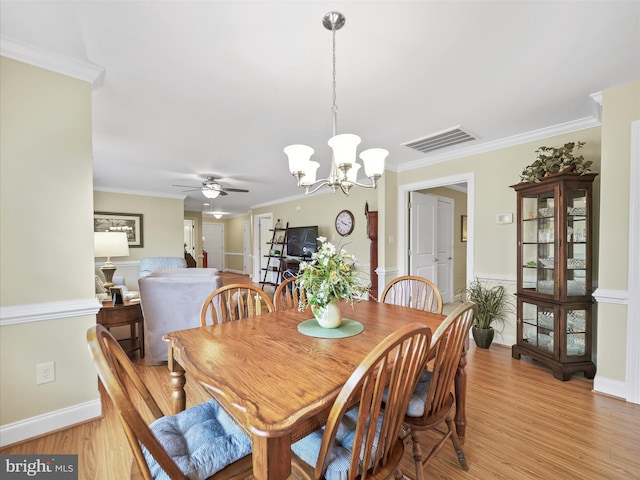 dining room featuring ornamental molding, visible vents, light wood-style flooring, and ceiling fan with notable chandelier