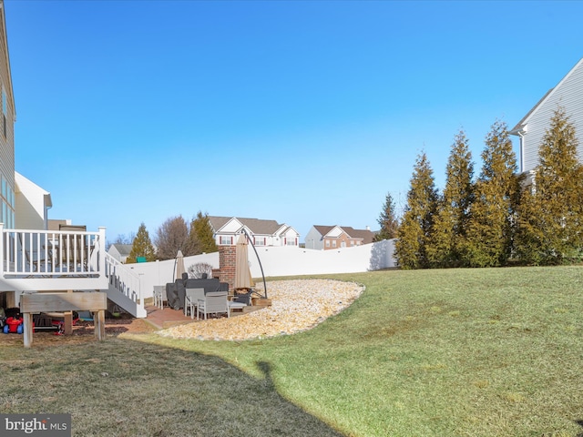 view of yard with a deck, a patio, a fenced backyard, and a residential view