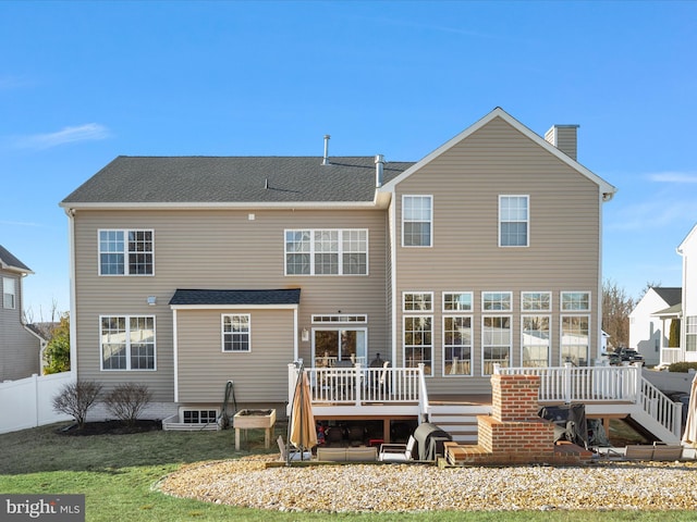 back of property featuring a chimney, roof with shingles, fence, a deck, and a yard