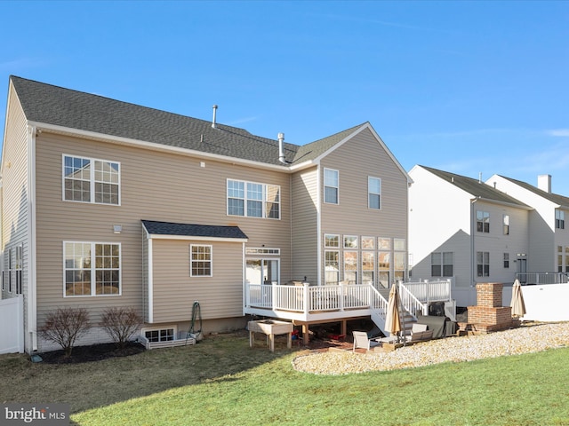 rear view of house featuring a shingled roof, fence, a deck, and a lawn