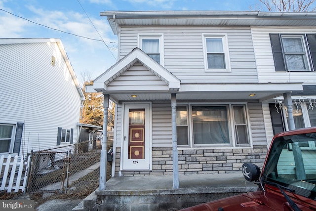 townhome / multi-family property with stone siding and fence