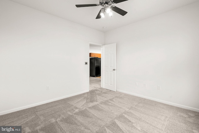 empty room featuring a ceiling fan, light colored carpet, and baseboards