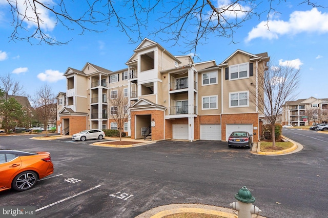 view of building exterior with a garage, a residential view, and uncovered parking