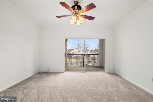 carpeted empty room with a ceiling fan, crown molding, and baseboards