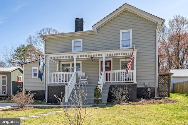 view of front of property with a front yard, covered porch, and a chimney