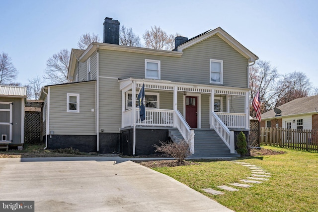 view of front facade with a front lawn, covered porch, a chimney, and fence