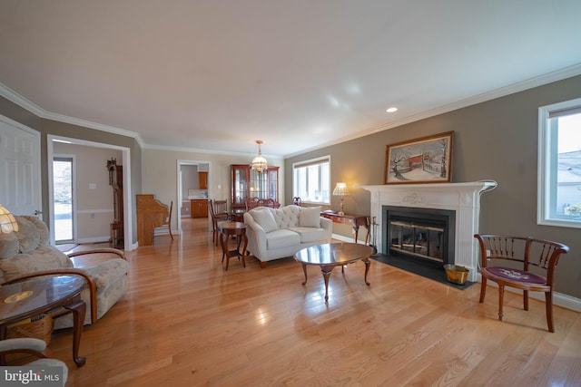 living area featuring a fireplace with flush hearth, light wood-style flooring, baseboards, and ornamental molding