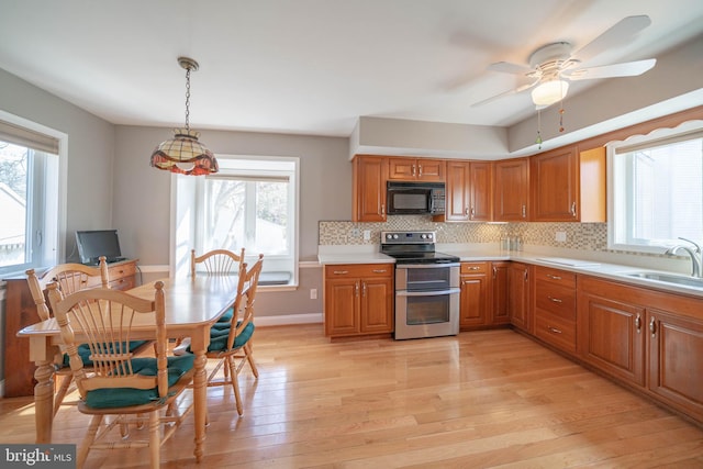 kitchen with a sink, double oven range, light wood-type flooring, and black microwave