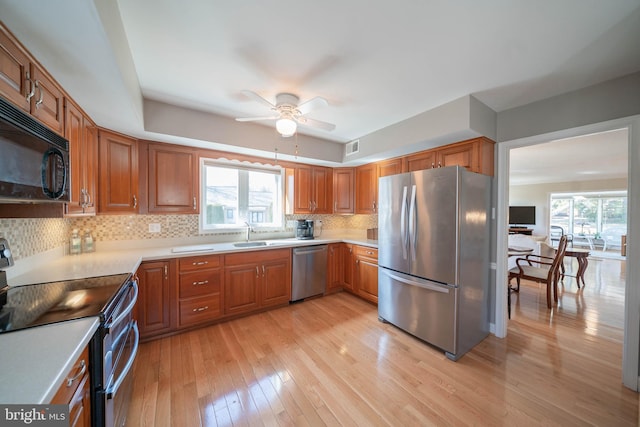 kitchen with a sink, light wood-style flooring, plenty of natural light, and stainless steel appliances