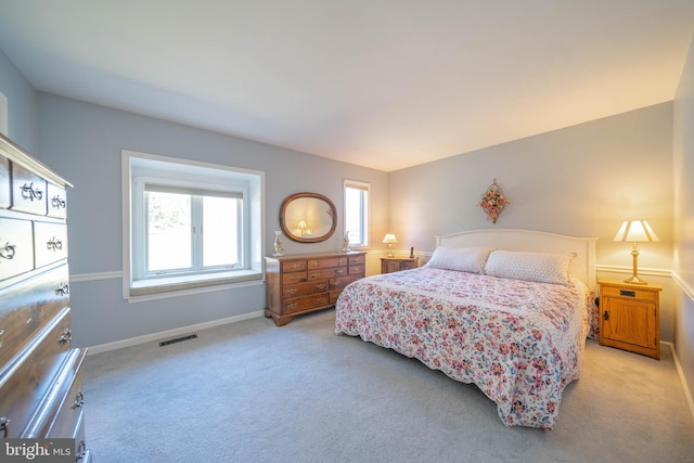 bedroom with baseboards, visible vents, and light carpet