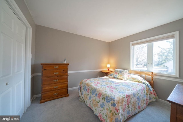 carpeted bedroom with a closet and baseboards