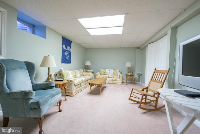 living room with concrete block wall, carpet flooring, and a paneled ceiling