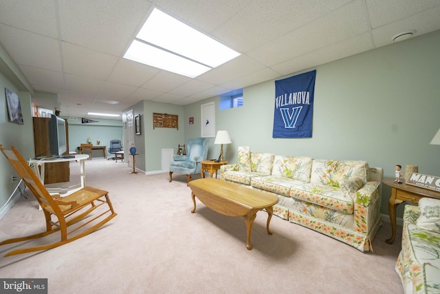 carpeted living area with a drop ceiling and baseboards