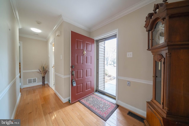 entrance foyer featuring visible vents, baseboards, light wood-style floors, and crown molding