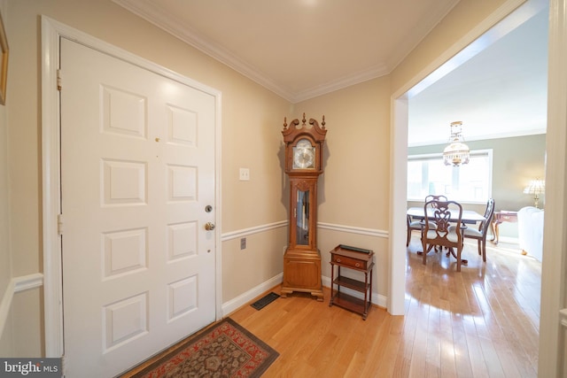 foyer featuring light wood finished floors, visible vents, baseboards, and ornamental molding