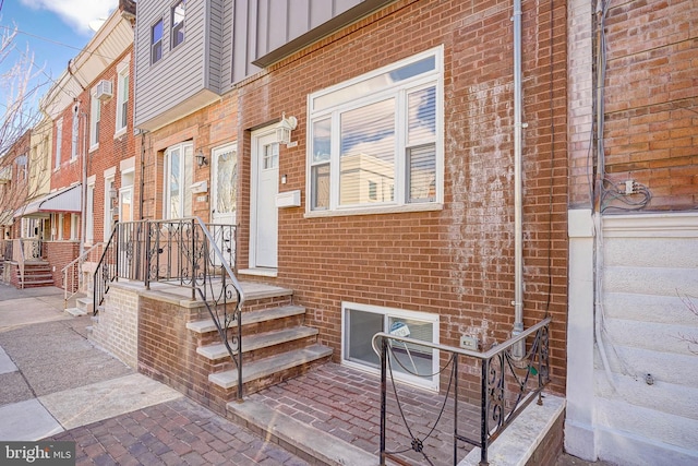 doorway to property featuring board and batten siding and brick siding