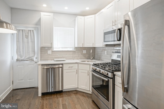 kitchen with a sink, white cabinets, appliances with stainless steel finishes, decorative backsplash, and dark wood finished floors