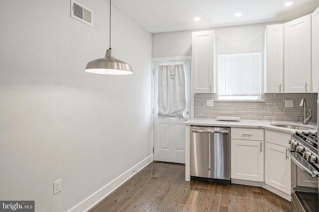 kitchen featuring tasteful backsplash, visible vents, stainless steel appliances, white cabinetry, and a sink