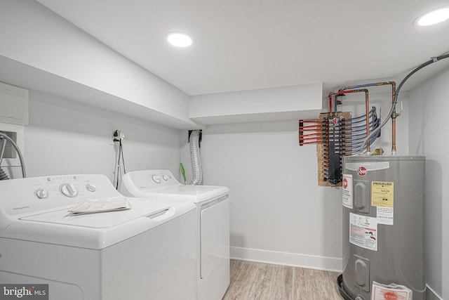 clothes washing area featuring laundry area, baseboards, electric water heater, light wood-style floors, and separate washer and dryer