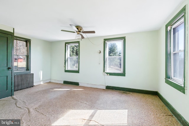 unfurnished room with radiator, carpet, baseboards, and a ceiling fan