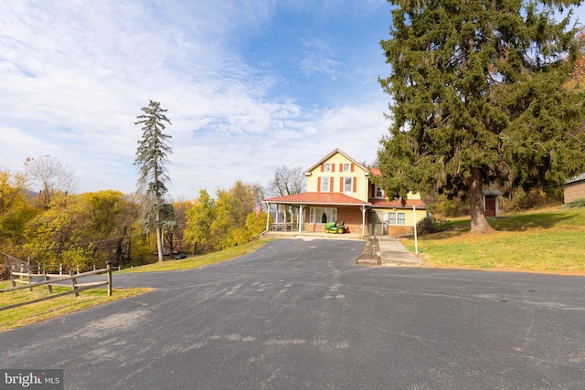 view of front facade with aphalt driveway, a front lawn, and fence