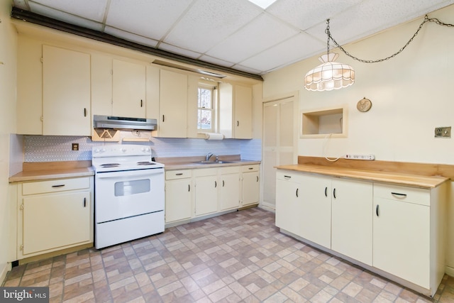 kitchen with a drop ceiling, under cabinet range hood, light countertops, backsplash, and white range with electric cooktop