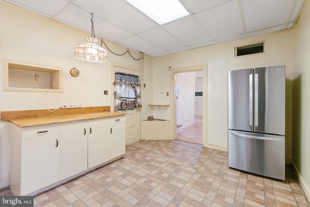 kitchen featuring white cabinets, light countertops, a drop ceiling, and freestanding refrigerator