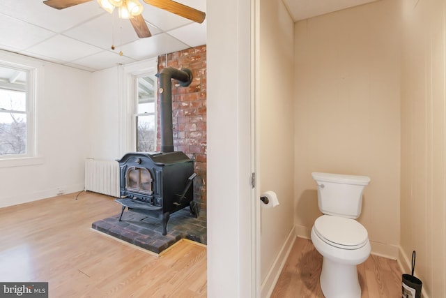 bathroom featuring plenty of natural light, wood finished floors, a wood stove, and radiator