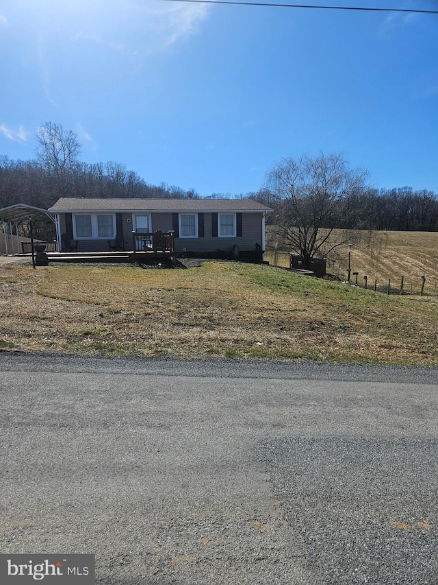 view of front of home with a detached carport, a front lawn, and fence