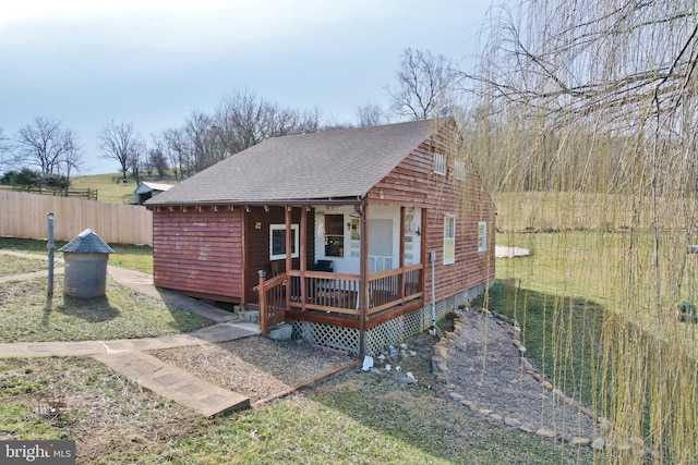 view of front of property with a porch, a shingled roof, and fence