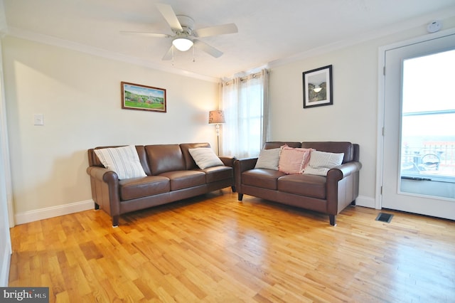 living area with a wealth of natural light, light wood-style flooring, and ornamental molding