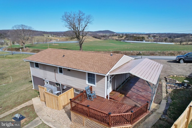 exterior space featuring a deck, a yard, and a shingled roof