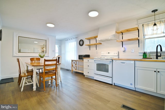 kitchen with open shelves, premium range hood, wood finished floors, white appliances, and a sink