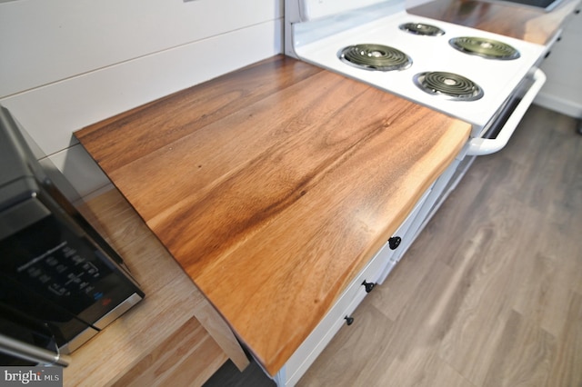 room details with wood finished floors and white range with electric stovetop