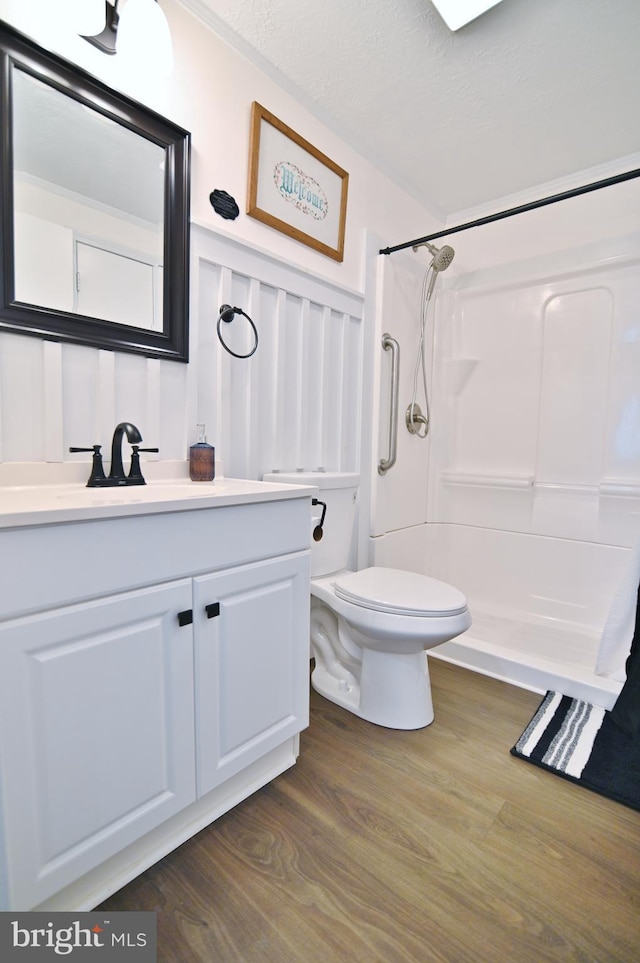 bathroom with toilet, vanity, walk in shower, and wood finished floors