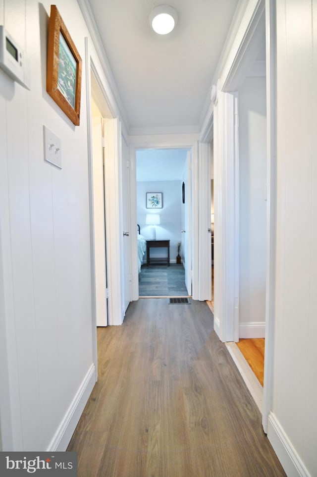 hall with visible vents, dark wood-type flooring, and baseboards