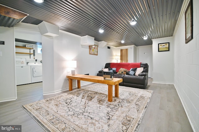 interior space featuring washing machine and dryer, concrete block wall, baseboards, and wood finished floors