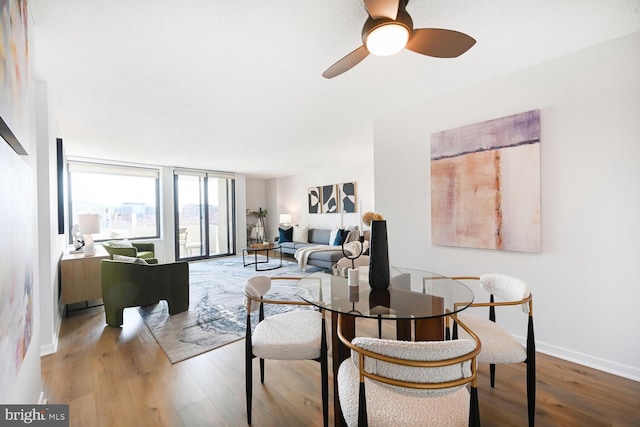 living room with a ceiling fan, baseboards, and wood finished floors