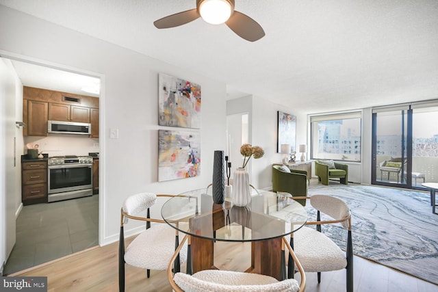 dining space with light wood-type flooring, baseboards, visible vents, and a ceiling fan