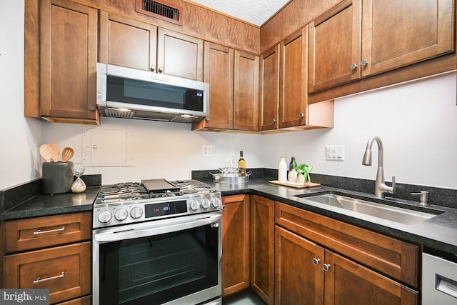 kitchen with brown cabinets, visible vents, appliances with stainless steel finishes, and a sink