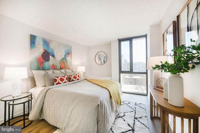 bedroom featuring expansive windows, baseboards, and wood finished floors