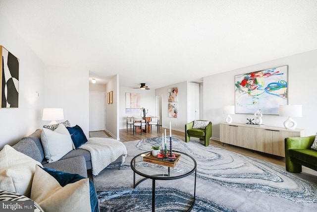 living room featuring a ceiling fan, baseboards, and wood finished floors