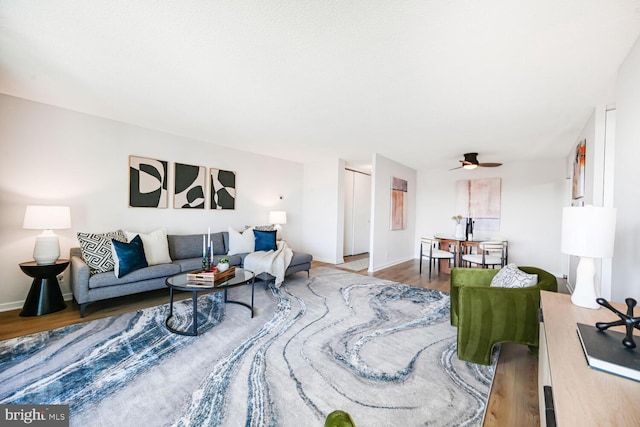 living room featuring wood finished floors, baseboards, and ceiling fan