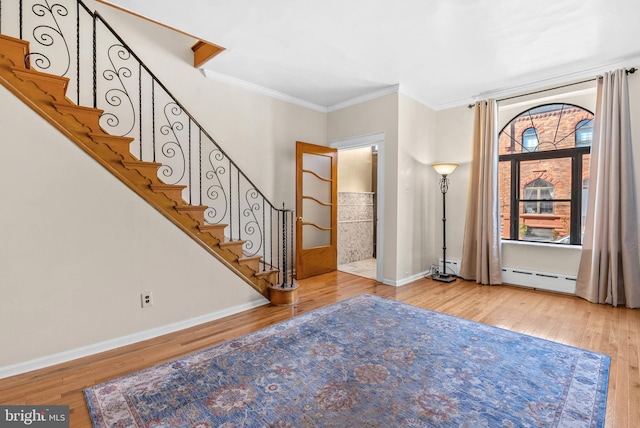 entrance foyer featuring ornamental molding, baseboard heating, and wood finished floors